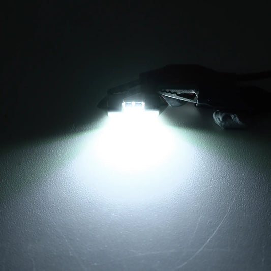 Bright white LED festoon bulb illuminated in a dark environment, emitting a strong focused light beam, highlighting the intensity and clarity of the automotive interior lighting.