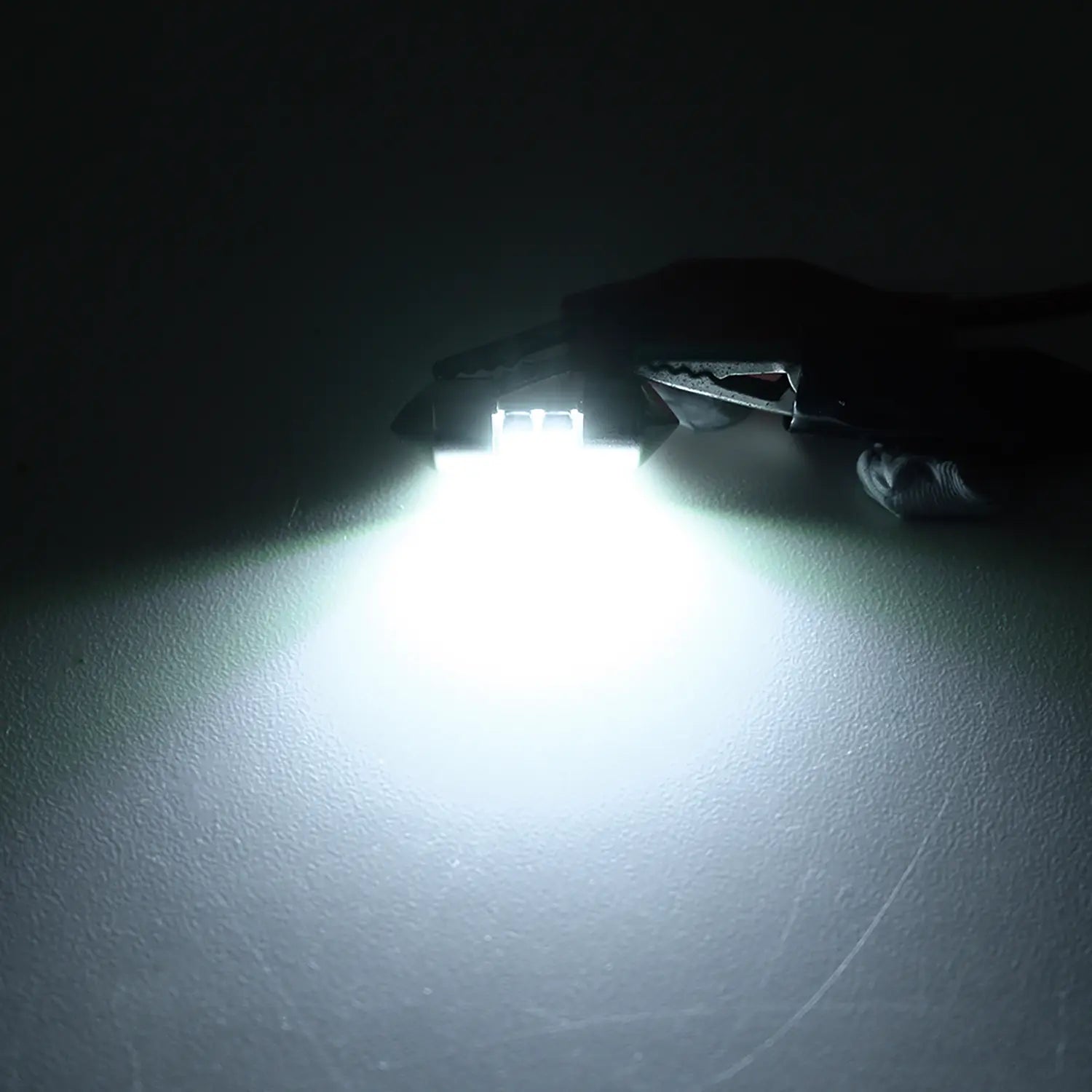 Bright white LED festoon bulb illuminated in a dark environment, emitting a strong focused light beam, highlighting the intensity and clarity of the automotive interior lighting.