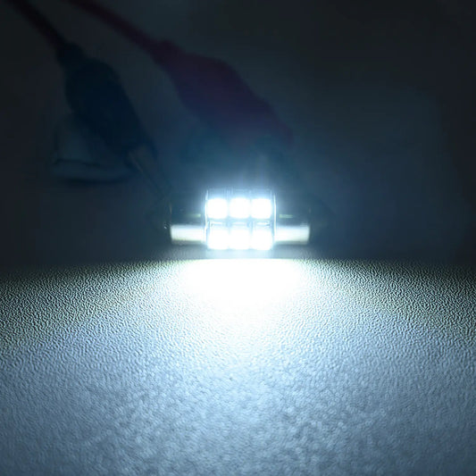 Bright white LED festoon bulb illuminated in a dark environment, emitting a strong focused light beam, highlighting the intensity and clarity of the automotive interior lighting.