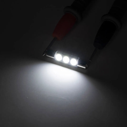 Bright white LED festoon bulb illuminated in a dark environment, emitting a strong focused light beam, highlighting the intensity and clarity of the automotive interior lighting.