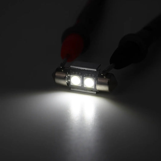 Bright white LED festoon bulb illuminated in a dark environment, emitting a strong focused light beam, highlighting the intensity and clarity of the automotive interior lighting.
