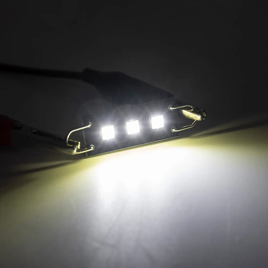 Bright white LED festoon bulb illuminated in a dark environment, emitting a strong focused light beam, highlighting the intensity and clarity of the automotive interior lighting.