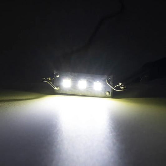 Bright white LED festoon bulb illuminated in a dark environment, emitting a strong focused light beam, highlighting the intensity and clarity of the automotive interior lighting.