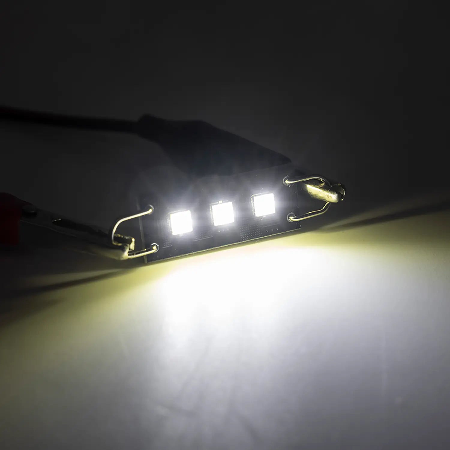 Bright white LED festoon bulb illuminated in a dark environment, emitting a strong focused light beam, highlighting the intensity and clarity of the automotive interior lighting.